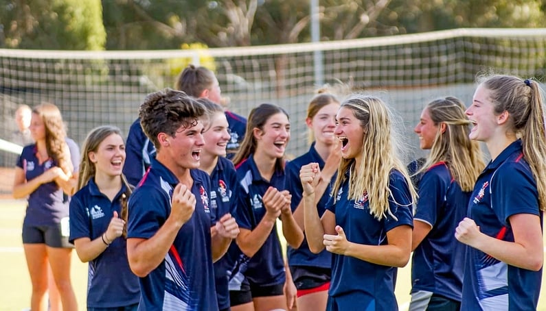 a group of Australian high school students in sport class playing on sport they are all in uniform and are cheering because they won a game the males and females are ged 1718-1
